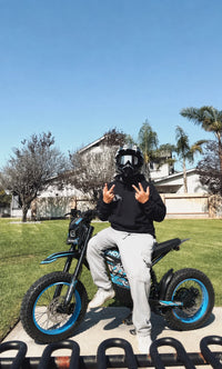Rider making a peace sign on a blue Buzymoto electric dirt bike