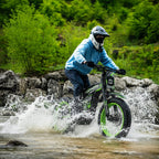 Rider in helmet crossing a creek on Buzymoto DAT70 green electric dirt bike with water splashing