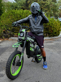 Rider in leather gear on a green Buzymoto electric dirt bike from Dirt Bike Mall