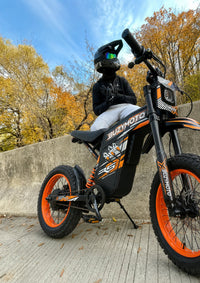 Rider exploring autumn scenery on an orange Buzymoto electric dirt bike