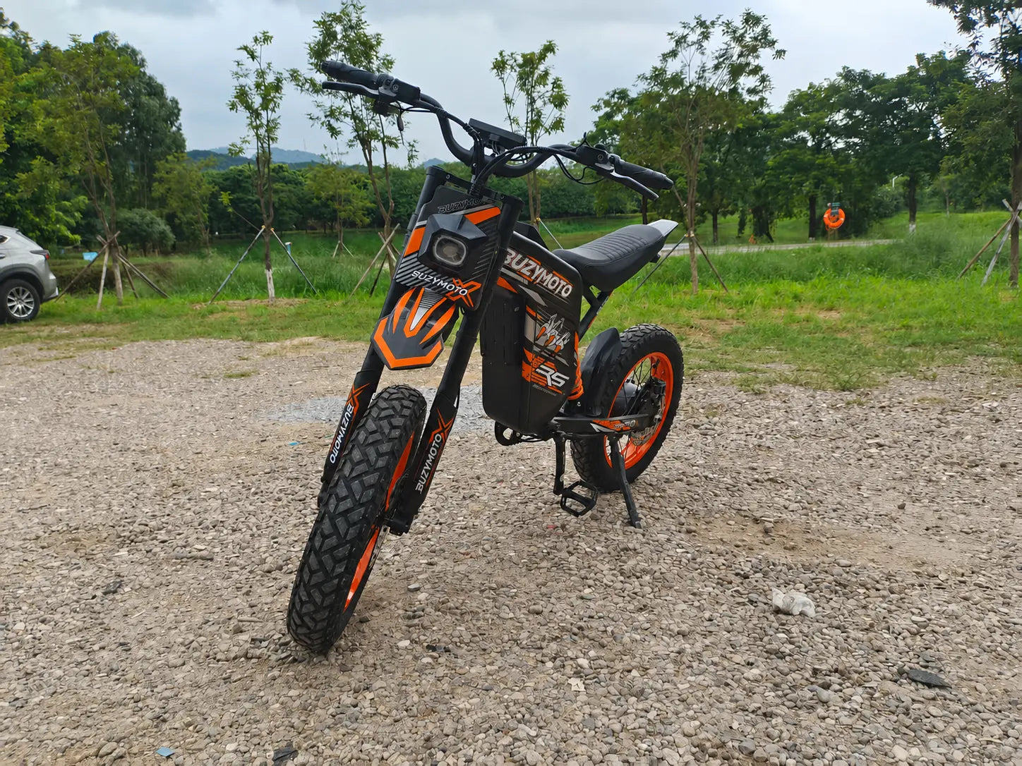 Orange Buzymoto electric dirt bike parked outdoors, available from Dirt Bike Mall