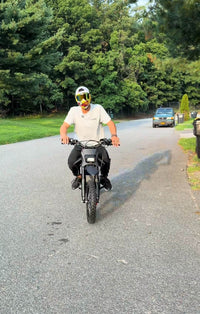Front view of a rider on a Terrawulf M7 electric dirt bike on a residential street, featured by Dirt Bike Mall