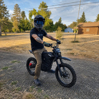 Rider with a Terrawulf M7 electric dirt bike in an open field, available from Dirt Bike Mall