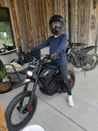 Rider with a Terrawulf M7 electric dirt bike outside a house porch, featured by Dirt Bike Mall