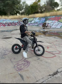 Helmeted rider riding a Terrawulf M7 electric dirt bike at a skatepark