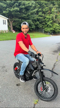 Smiling rider posing with a Terrawulf M7 electric dirt bike on a neighborhood street