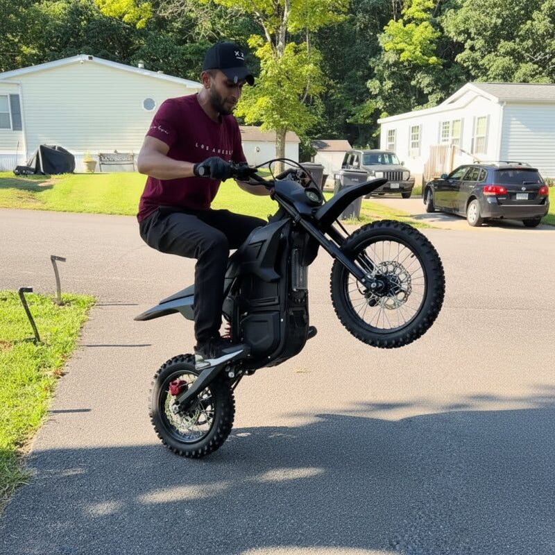 Rider performing a wheelie on Terrawulf M7 black electric dirt bike on a residential street